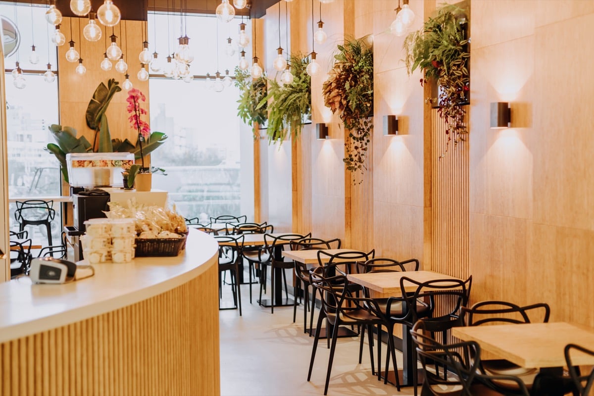 Växttavla Live Picture installerad på vägg i modern caféinteriör med bord och stolar