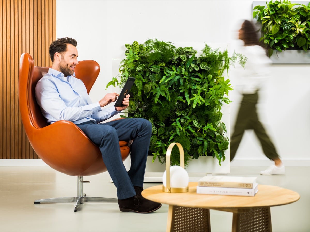 Rumsavdelare Live Divider Plus Vit 2 i modern inredning med växt. Man i orange stol vid träbord.
